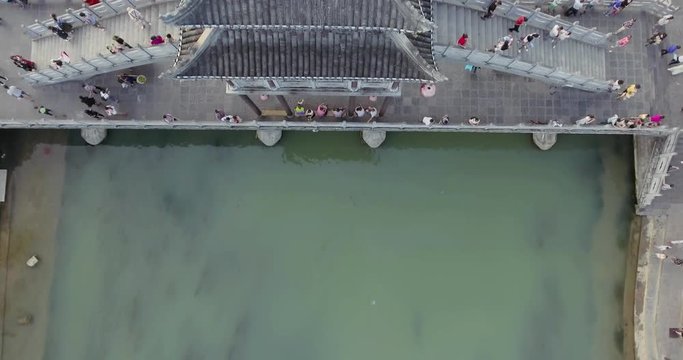 Top View or Aerial Shot of Famous Stone Old Fashioned Chinese Bridge in Ancient Town in Fenghuang County, China. Aerial View of Stone Bridge over Green River, Crowds of People.