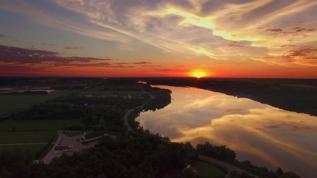 Moving aerial view of spectacular colorful sunrise over smooth river waters.

