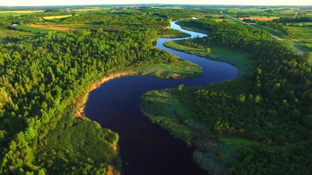 Pristine winding river amid rural wilderness, woodlands.
