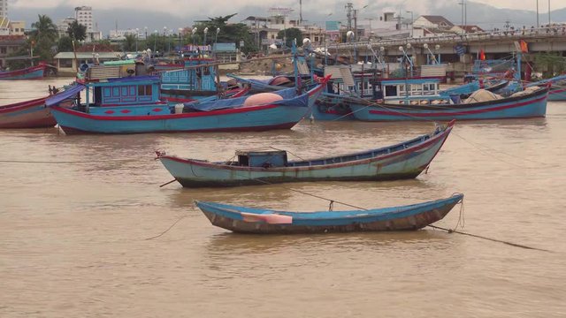 Vietnamese boats on a river at sunset. Busy bridge with lots of motorbikes. Nha Trang, Vietnam travel landscape and destinations.