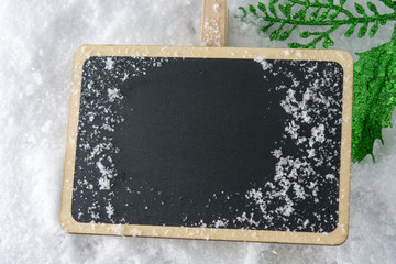 Blank blackboard on snow with Christmas decoration