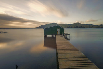 Otago peninsula coastal landscape scenery with green boat shed in sheltered water, Otago, South Island near Dunedin, New Zealand