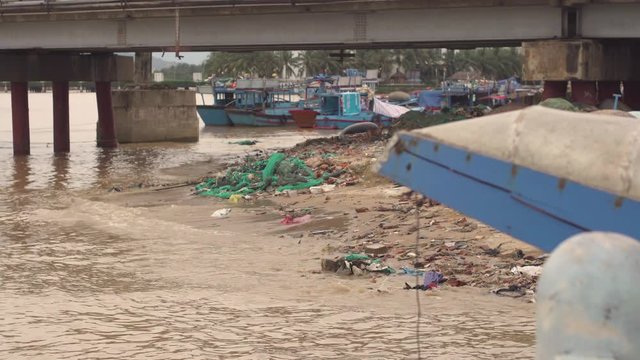 Riverside in Vietnam with lots of garbage. Fisherman's village. Polution of water and land.