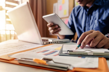 business documents on office table with smart phone and digital tablet and graph business with social network diagram and man working in the office