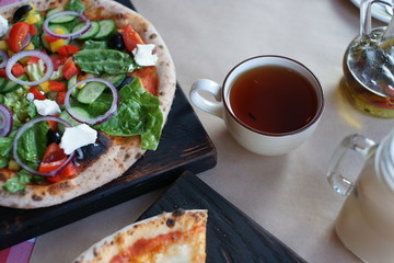 Two pizza with vegetables and cheese on the table.