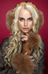 Beauty fashion woman portrait on red background with fur on head and hands. Blond girl with curly hair. 