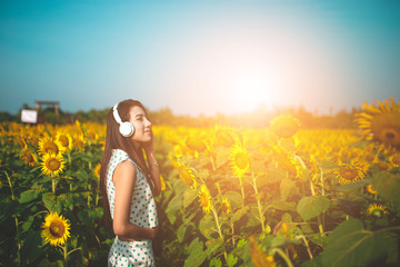 Obraz na płótnie Canvas beautiful girl listening to music in field of sunflowers