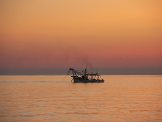 Fishing boats pull their nets at the sunrise. Adriatic cost. Emilia Romagna. Italy.