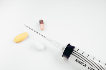 Medication in tablets and capsules and insulin syringe on white  background,Empty syringe