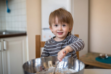 Toddler boy with  bowl in the kitchen making dough, childhood, r