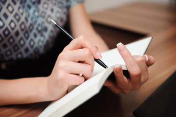 Fototapeta premium Closeup of a female hand writing on an blank notebook with a pen