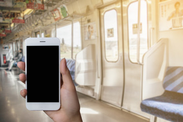Person hand holding smartphone or mobile phone with white screen using in skytrain for checking or shooting picture.
