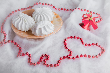 White airy zephyrs in the dish on the soft cloth with a little decorative Christmas bell and small balls chain. Very beautiful surprise for someone in special moment.. Romance. Focus on the zephyrs.
