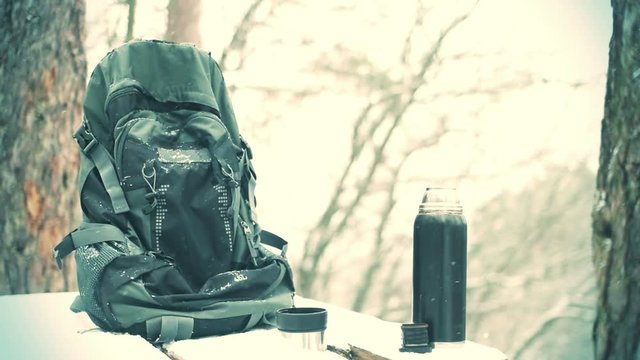 backpack and a thermos and falling snow