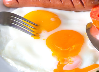 Piercing the yolk, American breakfast in white dish