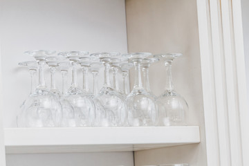A lot of empty wine glasses in a row in white interior