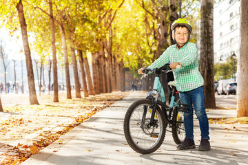 Smiling boy with his bike at autumn park