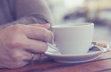 Man's hand holding a cup of coffee cafes.Close up a cup of coffee on old wooden background