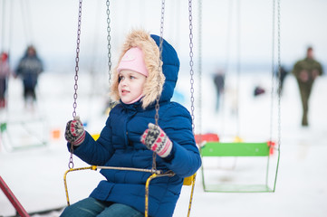 Little girl swinging on a chain swing in winter