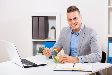 Businessman is sitting in his office and having lunch break.