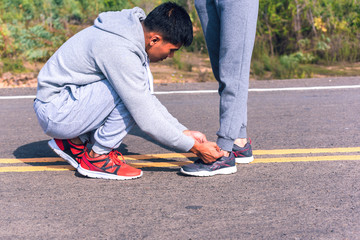 handsome man Tie shoelaces for girlfriend before jogging on road  ; Healthy lifestyle love couple of cardio together in outdoors.
