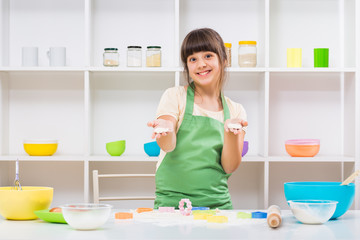 Obraz na płótnie Canvas Happy little girl enjoys making cookie.
