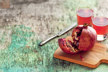 Fresh pomegranate juice and pomegranate. Pomegranate and glass of pomegranate juice on a wooden textural background. Healthy drink. Red Green