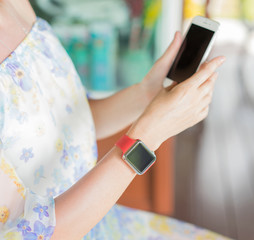  Youth and technology. Womans hands  with smartwatch and smartphone. Focus on smartwatch.