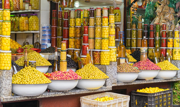 Market stall selling fresh olives and bottled food in the main souk of Marrakesh, Morocco.