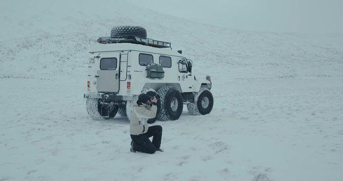 Young man photographer with professional camera taking pictures of beautiful winter snowy landscape. Yamal 2016. 4k red epic

