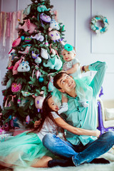 Fototapeta na wymiar The father with daughters sitting near christmas tree
