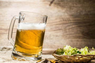 Big mug with beer foam stands on linen cloth