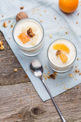 Fresh homemade dessert with biscuits, yogurt, tangerines and walnuts, served in a glass