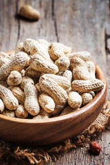 Peanuts in shell in a wooden bowl, selective focus