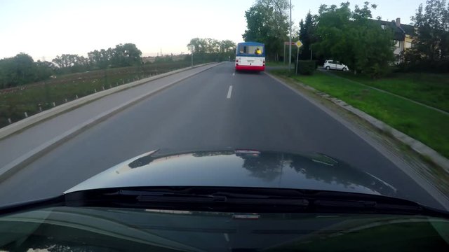 car overtakes bus on the long road near by the city - view from car roof