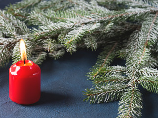 Dark christmas background with red candle and fir tree branches