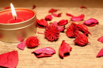 burning red candle on the table with petals and flowers