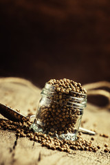 Fototapeta premium Coriander seeds in jar, rustic style, selective focus