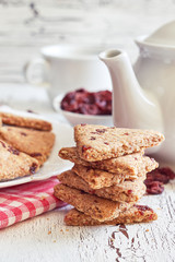 Stack of whole wheat cookies with dried cranberries on white rustic wooden background