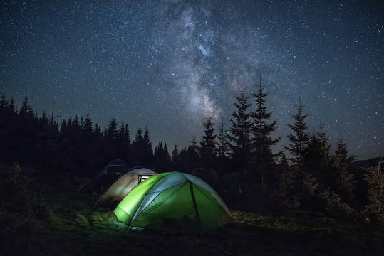 Tourists tents in the wood under the Milky Way