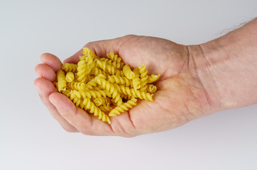Hand holding fusilli noodles isolated