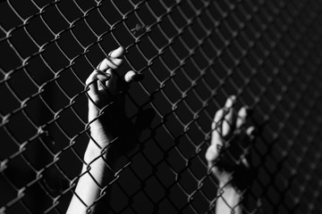 Hand holding on chain link fence..