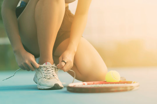 Tennis player tying shoelaces in tennis count.
