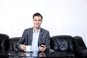 male young adult businessman in suit sitting on a leather sofa w