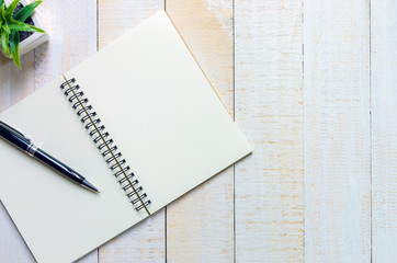 black pen place on notebook place on white wooden table