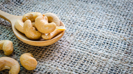 cashew nuts salted and roasted in wooden spoon place on hemp bac
