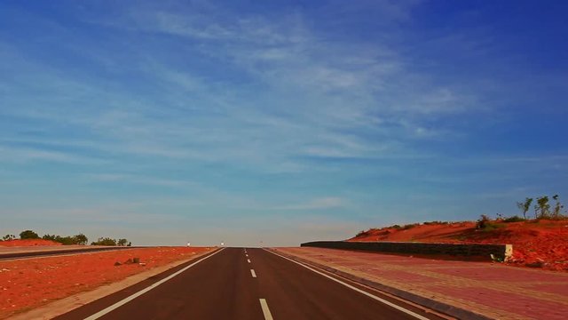 camera moves along asphalt road with signs towards infinity among boundless brown sand dunes under blue sky