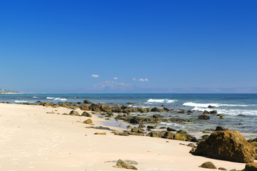 The beach of Atlantic ocean with a lot of rocks on the foreground. Copy space for text.