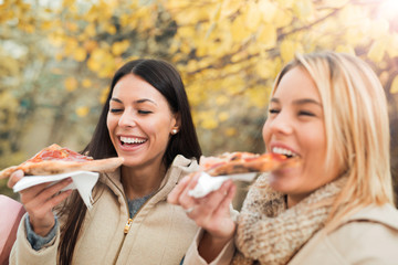 Friends eating pizza. Two young women eating pizza after shoppin