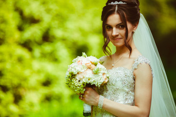 young and beautiful bride with bouquet of flowers standing in th